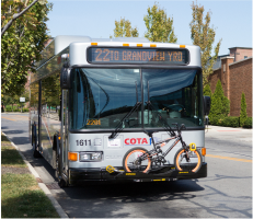 A COTA bus that is displaying “22: To Grandview Yard”, stopped on the road. A bike is on the bike rack on the front of the bus.